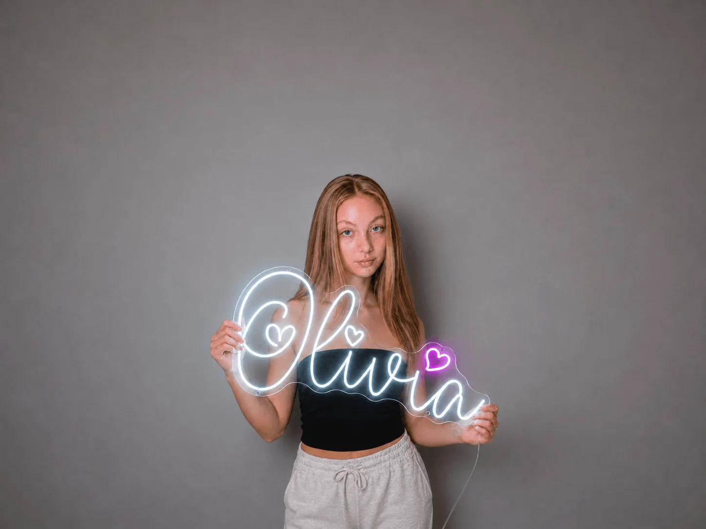 A custom white Olivia LED neon name sign with pink hearts