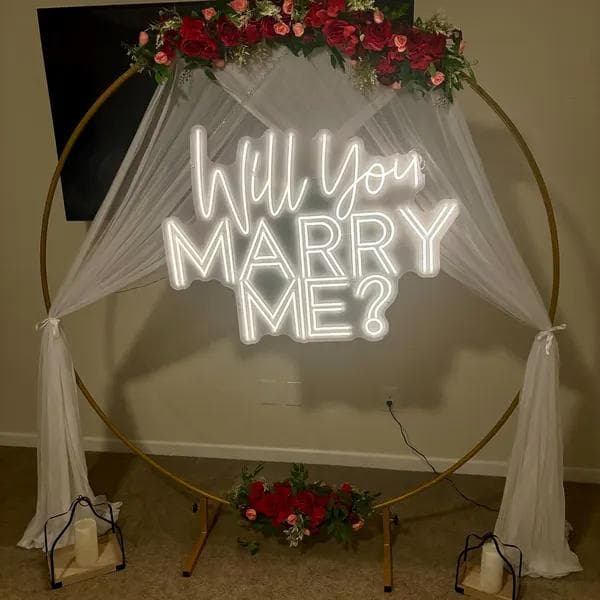 Romantic warm golden custom script wedding neon sign mounted on a lush circular flower arch at a wedding reception